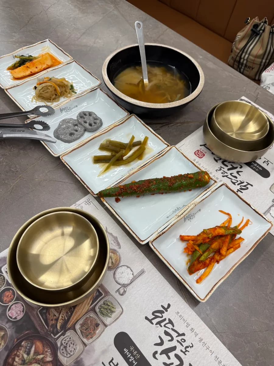 Table setting with banchan and napa cabbage doenjang soup before the grilled fish meal