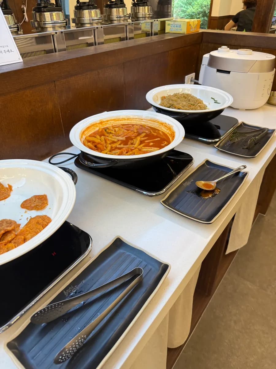 Self-serve side dishes including tteokbokki and japchae mentioned in the review