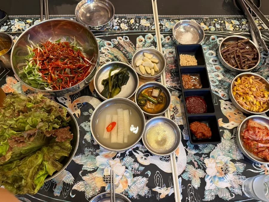Table dressée avec légumes pour ssam, dongchimi, sauces et pickles chez Gwanghuijeong