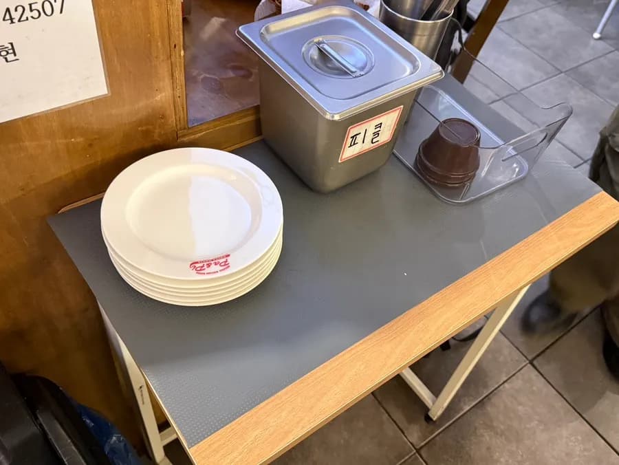 Platos y pepinillos de autoservicio con condimentos de mesa en P&P Pasta House