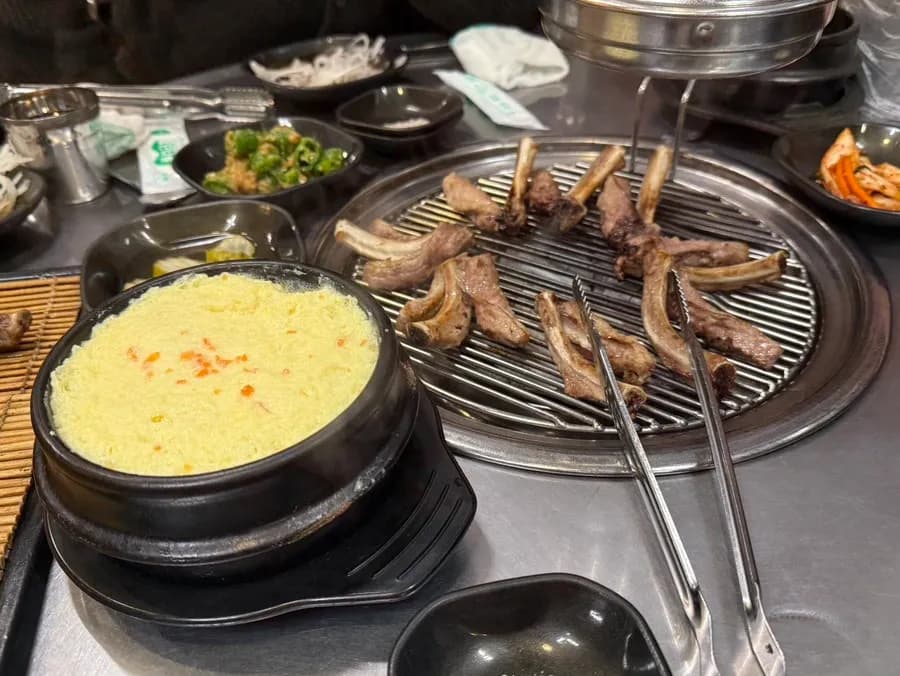 Banchan cơ bản với kimchi, ớt xanh, dưa muối, hành ngâm và canh chả cá nóng