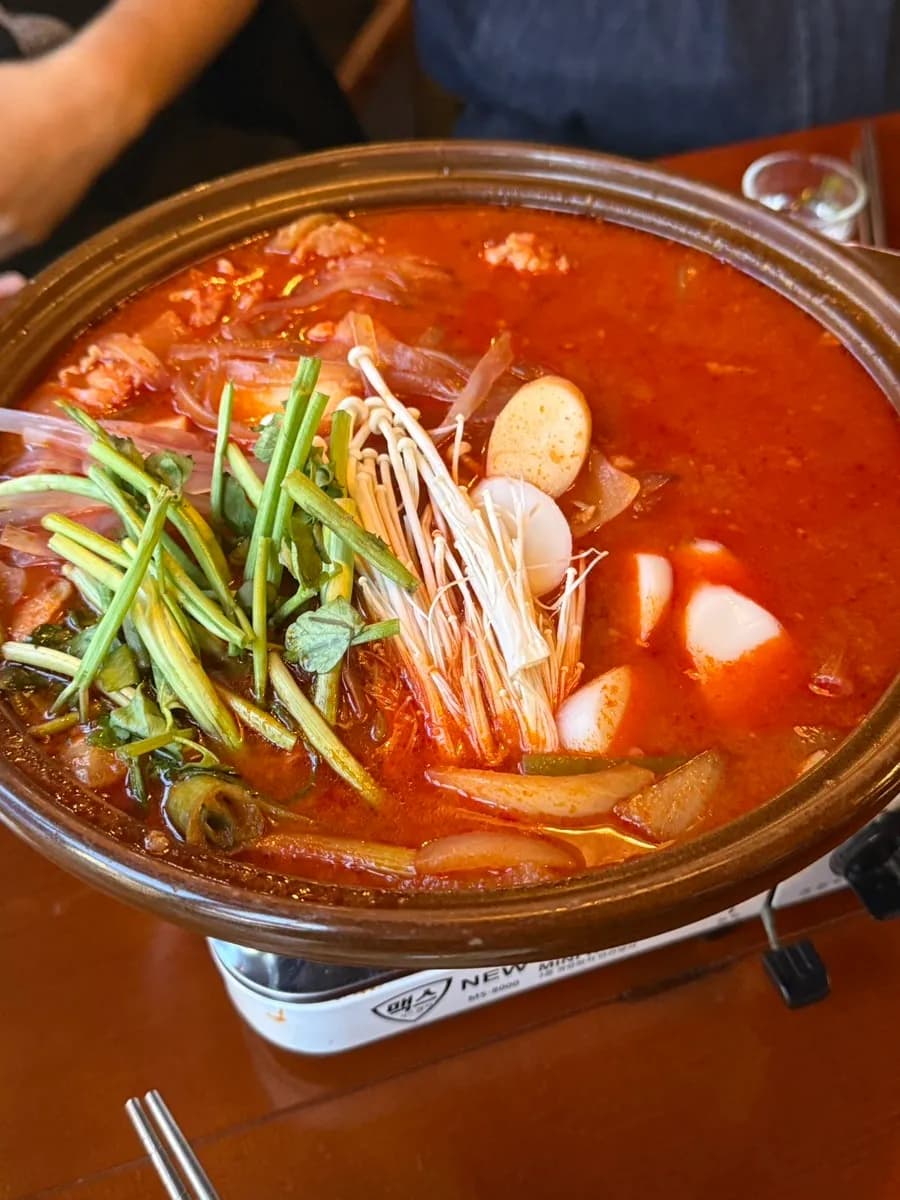 Gopdoritang servido con gopchang, pollo, minari, pasteles de arroz y setas enoki